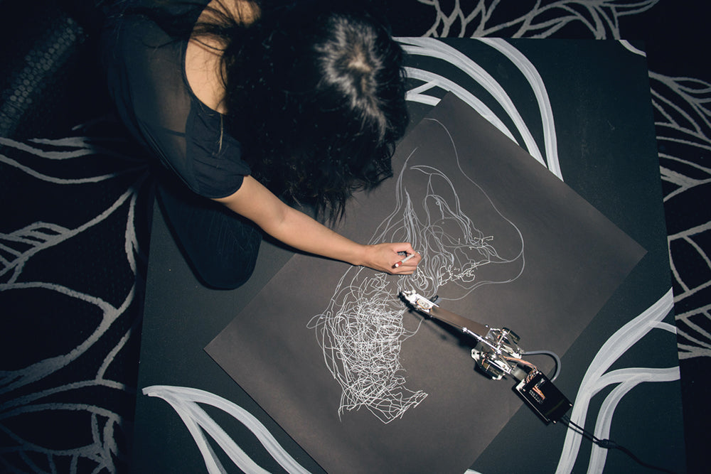 The artist Sougwen Chung collaborating with D.O.U.G._1 (Drawing Operations Unit: Generation_1) on the performance Drawing Operations, 2015. PHOTO DREW GURIAN.